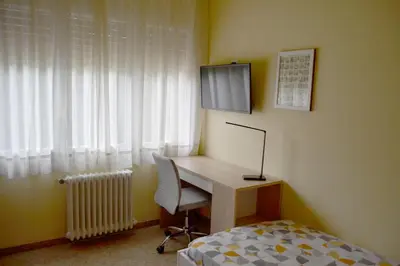 a bedroom with a desk and a television and a bed at Cal Kim in Martorell