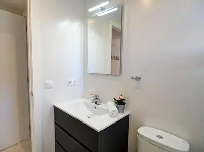 a bathroom with a sink and a mirror and a toilet at Carreta Sea Views by Hello Homes Sitges in Sitges