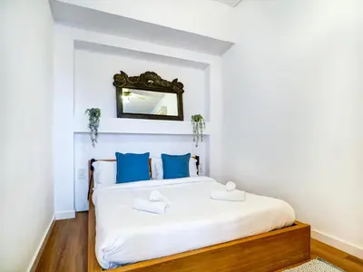 a bedroom with a bed with blue pillows and a mirror at La Cubana Apartment by Hello Homes Sitges in Sitges