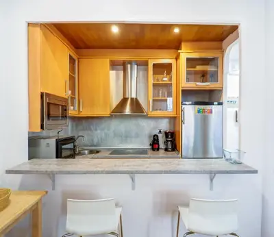a living room with a blue couch and a kitchen at La Cubana Apartment by Hello Homes Sitges in Sitges