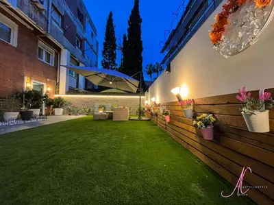 a backyard with a green lawn and a building at Arena Castelldefels in Castelldefels
