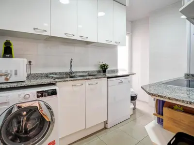 a white kitchen with a washing machine in it at Golden Sands by Hello Homes Sitges in Sitges