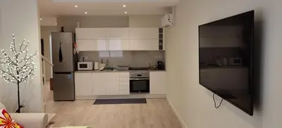 a kitchen with white cabinets and a stainless steel refrigerator at BARCELONA DUPLEX DE 3 HABITACIONES in Hospitalet de Llobregat