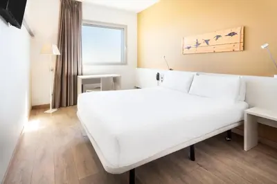 a hotel room with a white bed and a window at B&B HOTEL Barcelona Viladecans in Viladecáns