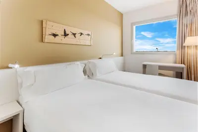 a white bed in a room with a window at B&B HOTEL Barcelona Viladecans in Viladecáns