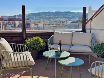 a patio with a couch and a table with wine glasses at Atic Barcelona in Barcelona