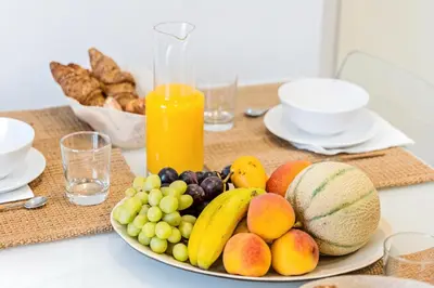 a plate of fruit on a table with a bottle of orange juice at Sweett - La Villarroel in Barcelona