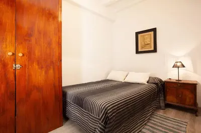 a small bedroom with a bed and a wooden door at Esquirol in Barcelona