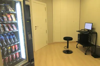 a room with a computer and a stool in front of a refrigerator at Hostal Aslyp 114 in Barcelona