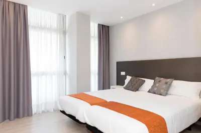 a bedroom with a large white bed and windows at Hostal Aslyp 114 in Barcelona