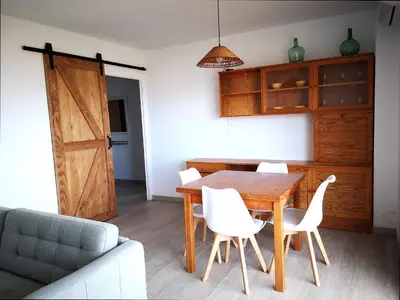 a dining room with a wooden table and white chairs at ÁTICO FRENTE AL MAR in Canet de Mar