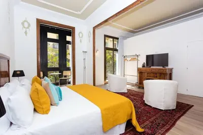 a bedroom with a bed and two white chairs at Luxury 4bdr In Gracia in Barcelona