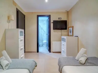a small room with two beds and a television at Villa Nirvana by Hello Homes Sitges in Sitges