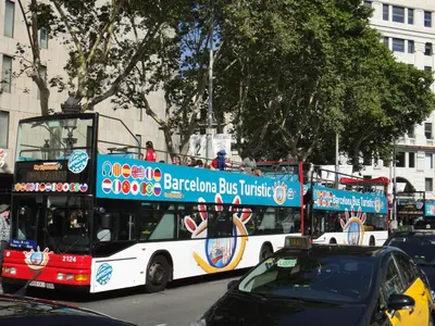a double decker bus driving down a city street at Hostal Live Natura Barcelona in Barcelona