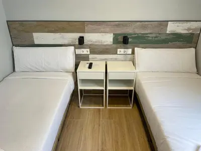 two beds in a room with a table between them at Hey Rooms in Cerdanyola del Valles