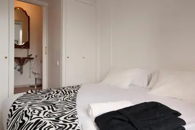 a white bed with a black and white blanket on it at Sagrada Familia 4 Bedrooms 