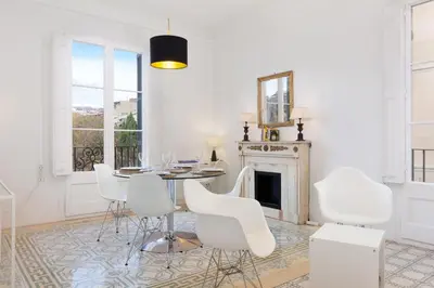 a dining room with white chairs and a table and a fireplace at Sagrada Familia 4 Bedrooms 