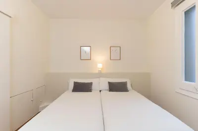 a white bedroom with a large white bed with two pillows at SibsBcn-Paseo de Gracia Luxury Exclusive Gaudí in Barcelona