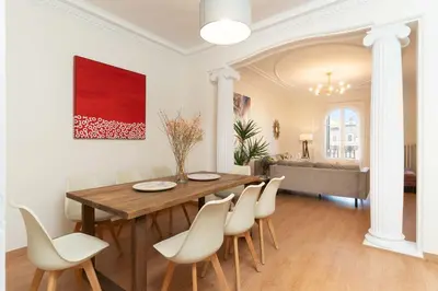 a dining room with a wooden table and white chairs at SibsBcn-Paseo de Gracia Luxury Exclusive Gaudí in Barcelona
