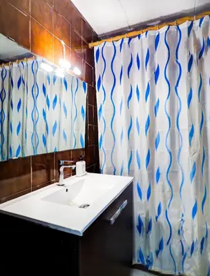 a bathroom with a sink and a shower curtain at Ferdinand Apartment by Hello Homes Sitges in Sitges