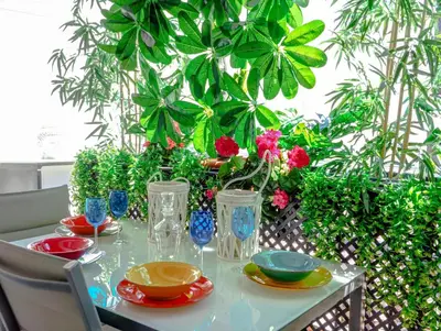 a table with plates and vases on it with plants at Flamingo Apartment by Hello Homes Sitges in Sitges