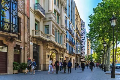 a group of people walking down a street next to buildings at Habitat Apartments Batlló in Barcelona