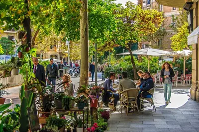a group of people sitting at tables in a garden at Habitat Apartments Batlló in Barcelona