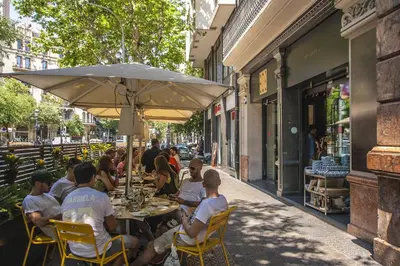 a group of people sitting at a table under an umbrella at Habitat Apartments Pedrera in Barcelona