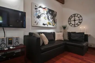 a living room with a black couch and a clock at Habitat Apartments Ferran in Barcelona