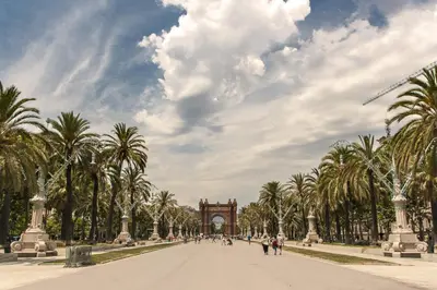 a street in a park with palm trees and a clock tower at Habitat Apartments Carders in Barcelona