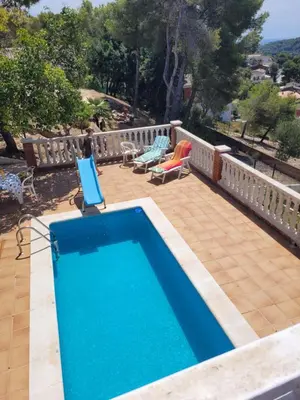 a swimming pool on a patio with two chairs and a table at Cal Jamila in Cubelles