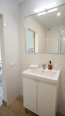 a white bathroom with a sink and a mirror at Holidays en Arenys de Mar y Montaña in Arenys de Mar