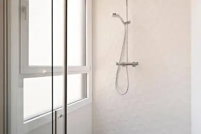 a white bathroom with a toilet and a window at The Collection Barcelona - Arc de Triomf Luxury Modern 2-Bedroom 2-Bathroom in Barcelona