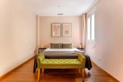 a bedroom with a bed with a green bench at The Collection Barcelona - Elegant 3-bedroom Apartment in the Heart of BCN in Barcelona