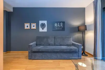 a blue couch in a living room with a glass table at The Collection Barcelona - Modern and bright apartment in Eixample 1-3 in Barcelona