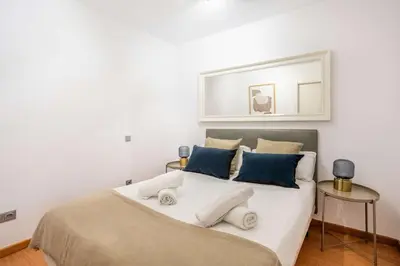 a bedroom with a large white bed with blue pillows at The Collection Barcelona - Pl Universitat Comfortable 3BD with private patio in Barcelona