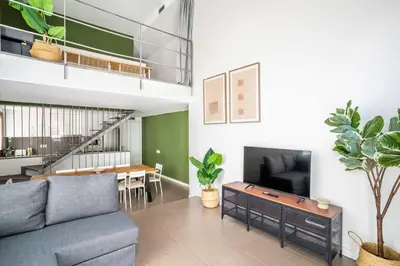 a living room with a couch and a tv and a table at The Collection Barcelona - Modern and bright 4BD triplex in Paralel! in Barcelona