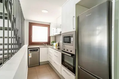 a kitchen with white cabinets and a stainless steel refrigerator at The Collection Barcelona - Modern and bright 4BD triplex in Paralel! in Barcelona