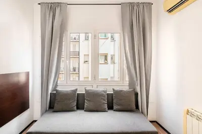 a window seat with pillows in front of a window at The Collection Barcelona - 4- Bedroom Apartment in Gracia Village in Barcelona