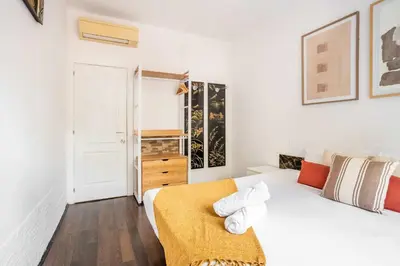 a white bedroom with a bed with a yellow blanket at The Collection Barcelona - 4- Bedroom Apartment in Gracia Village in Barcelona
