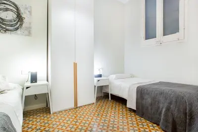 a white bedroom with two beds and a hallway at The Collection Barcelona - 4 bedroom apartment with a balcony in Las Ramblas 2 2 in Barcelona