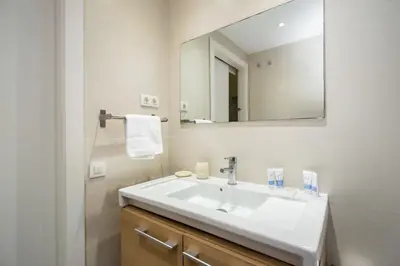 two beds in a room with white walls and wooden floors at The Collection Barcelona - Bright and modern 4bedroom with terrace in Las Ramblas P1 in Barcelona