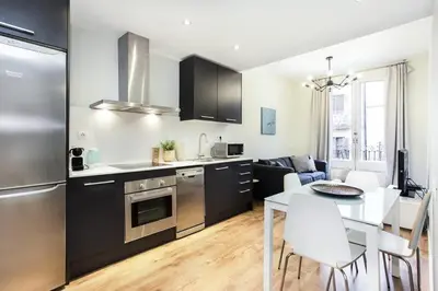 a white bedroom with a large bed and a table at The Collection Barcelona - Bright and modern 2bedroom in Las Ramblas 2 1A in Barcelona