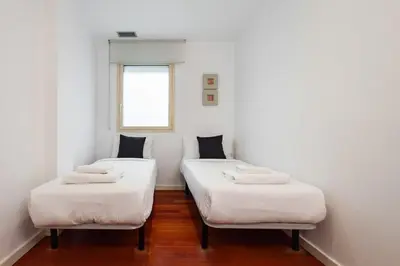 two beds in a room with white walls and a window at The Collection Barcelona - Plaça Catalunya Modern 2bedroom with balcony in Barcelona