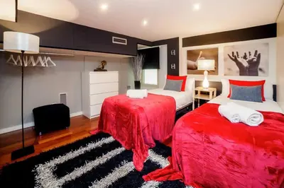 a bedroom with two beds with red sheets and a rug at The Collection Barcelona - Luxury Duplex Apartment in the Heart of Barcelona in Barcelona
