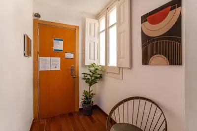 a hallway with a door and a chair and a plant at The Collection Barcelona - Plaza Urquinaona 3-Bedroom Suite in Barcelona