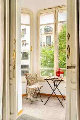 a chair and a table in a room with windows at The Collection Barcelona - Huge historic 5BD with private Terrace! in Barcelona