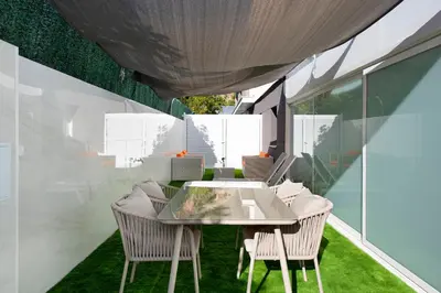 an outdoor dining area with a glass table and chairs at PLAYA a 3 minutos Parking barbacoa Apartamento en Castelldefels in Castelldefels