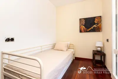 a small bedroom with a bed and a painting on the wall at Spacious Villa Santa Fe - private pool, big garden and A/C close to Sitges in Olivella
