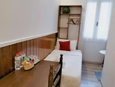 a small room with a bed and a table at Barcelona CoronaHostal in Badalona